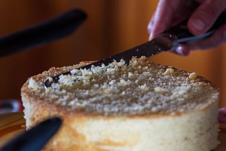 cleaning up the crumbs of the top layer of a vanilla cakeの写真素材