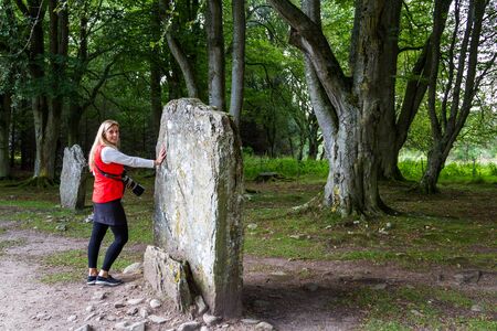 Tourist touching a large standing stone in a well preserved bronze age cemetery located near Inverness.の写真素材
