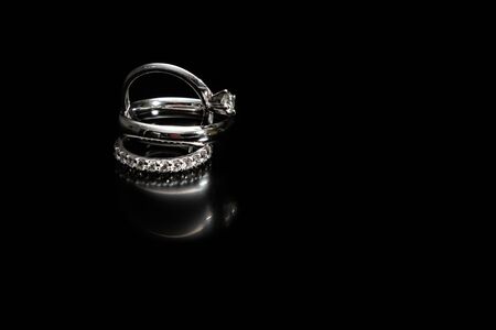 close up of engagement and wedding rings isolated on a black backgroundの写真素材