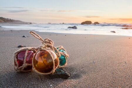 sunset in the Oregon coast with colorful glass floats on a a sandy beachの写真素材