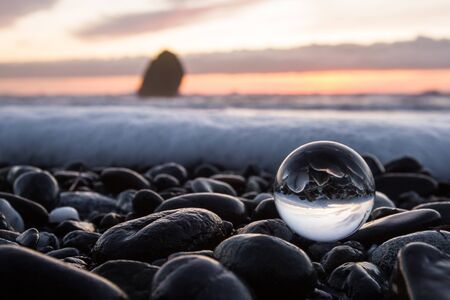 coastal sunset inverted on a clear glass sphere using a wide angle lens to capture a slightly blurred scene in the backgroundの写真素材