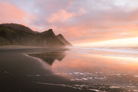 Gorgeous sunset scene in the Oregon coast with colorful clouds reflecting on the wet sand and waves...
