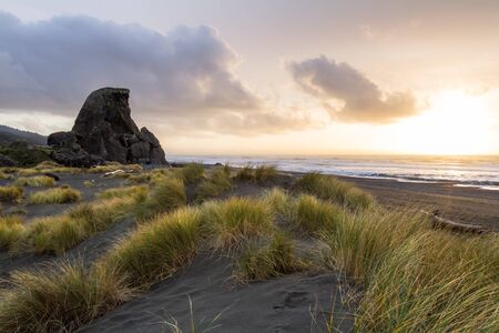 Beautiful afternoon in the southern Oregon Coast with the setting sun adding light and color to the clouds and a bit of reflected light on the tall grassの写真素材