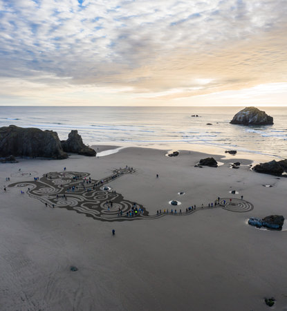 Bandon by the Sea, Oregon / USA - March 08 2020: People at sunset walking through a labyrinth on the beach of Face Rock State Park created by the team of Circles of the Sandのeditorial素材