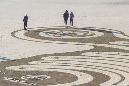 Bandon by the Sea, Oregon / USA - February 20 2020: People walking on the labyrinth made by the team of Circles in the Sand  in the flat sandy beach of Face Rock State Parkのeditorial素材