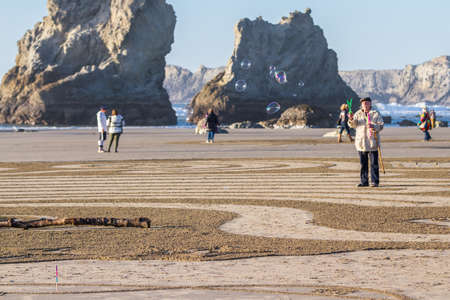 Bandon by the Sea, Oregon / USA - February 20 2020: Man making bubbles as people walk a labyrinth on the beach made by the team of Circles in the Sand in Bandon, Oregonのeditorial素材