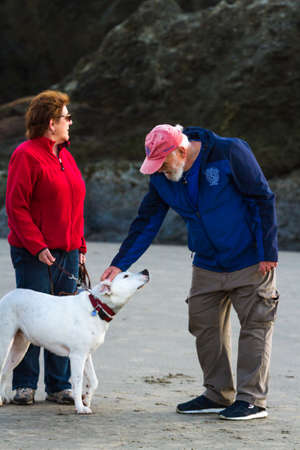 Bandon by the Sea, Oregon / USA - February 20 2020: Denny Dike labyrinth artist and founder of Circles in the Sand welcoming a friendly face and petting a dogのeditorial素材