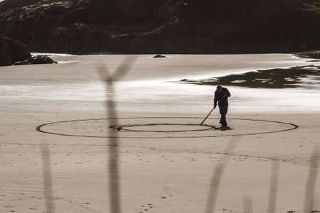 Bandon by the Sea, Oregon / USA - February 21 2020: Denny Dike, founder of Circles in the Sand drawing a walkable labyrinth in the flat sandy beach of Face Rock State Parkのeditorial素材