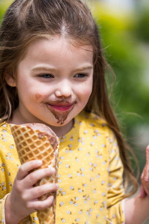 Close up of a happy young girl eating an ice cream cone outdoors