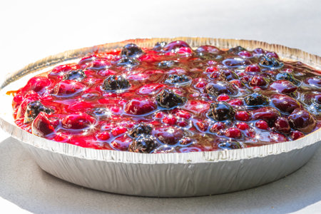 close up of a mixed berry pie under bright sunlight reflecting a beautiful sparkle on the shiny fruitの写真素材