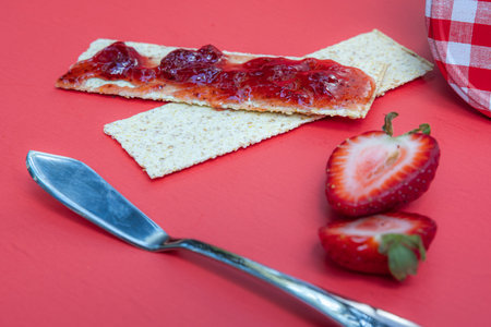 crackers and fresh strawberry jam isolated on a red background