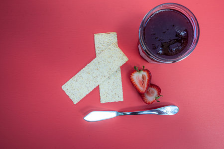 crackers and fresh strawberry jam isolated on a red background