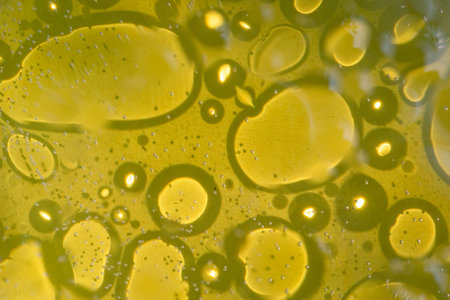 macro of olive oil drops on top of water as an abstract background