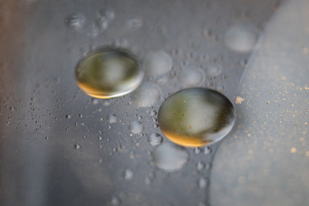 Oil drop with bubbles macro on top of water with a dark background