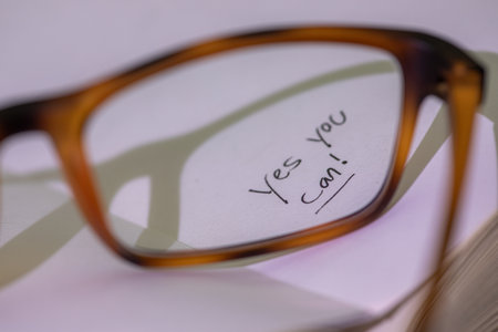 Hand written words that read Yes You Can seen thru eye glasses on a white page.の写真素材