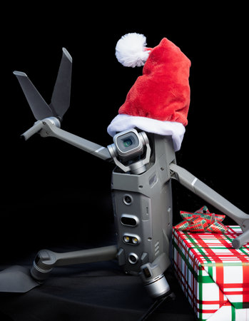 Portrait of a quadcopter drone wearing a santa hat as a Christmas concept on a dark background giving the peace sign.の写真素材