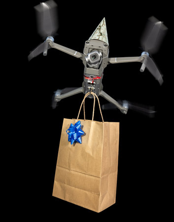 close up of a drone wearing a birthday hat delivering a gift isolated on a black backgroundの写真素材