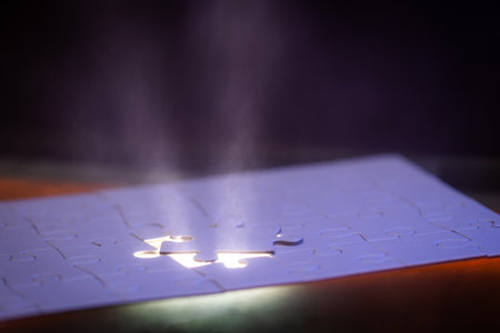 close up of a blank puzzle with a blue light and a beam of light from underneath as a concept.
