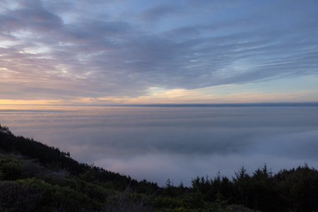 The sky is cloudy and the sun is setting. The clouds are white and the sky is blue