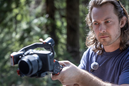 Content creator using a camera gimbal to film in nature with a blurred forest in the background