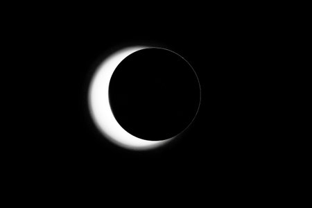 A black and white photo of a crescent moon. The moon is the main focus of the image, and it is the...