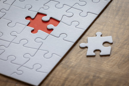 Blank puzzle with one missing piece next to the whole with a red placer where the last piece belongs. Concept for problem solving.の写真素材