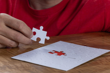 Blank puzzle with the missing piece being held next to the whole with a red placer where the last...