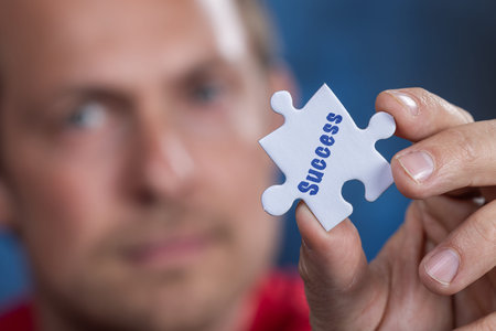 Concept for problem solving, a mans hand holding a blank puzzle piece with the man slightly out of...