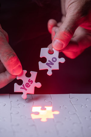 A person is holding two puzzle pieces with the words yes and no on them. Concept of making a...