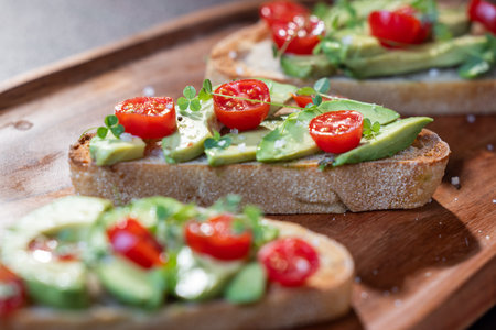 A slice of toasted sour dough bread with avocado and tomato on topの写真素材