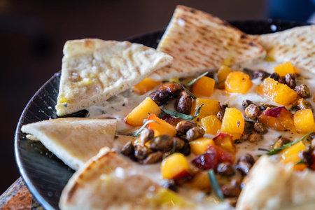 A plate of whipped ricotta with fresh roasted peaches and pitta slices served with a balsamic...