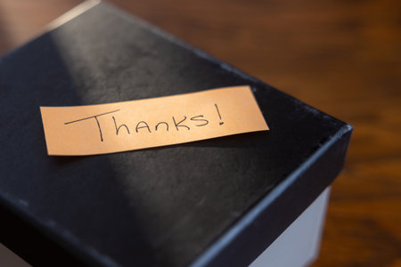 A box with a note that says Thanks written on it with a beam of light shining on the note.