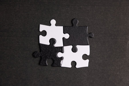 Opposite day concept using white and black puzzle pieces on a black background.の写真素材