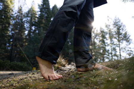 Human feet of an adult male walking barefoot in a forest as a form of grounding and connection to the earth.の写真素材