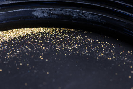 Closeup view of gold flakes collected in a black panning pan. Shiny metallic particles representing mining, prospecting, natural resources, and the search for wealth and treasure.の写真素材