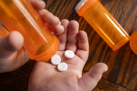A powerful conceptual photograph showing a child's hand reaching for colorful, unattended prescription pills or medication.の写真素材
