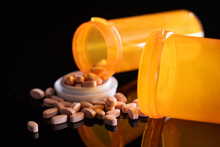 Pills and open prescriptions bottles on a black background as a healthcare concept.の写真素材