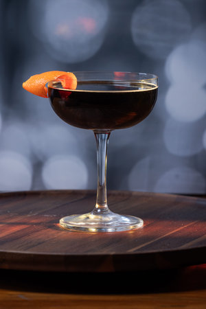sophisticated black coffee cocktail served in a coupe glass, garnished with a fresh orange peel...