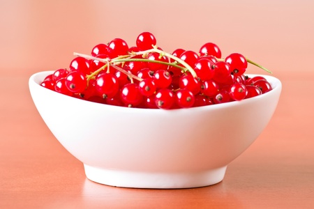 Red currant in ceramic bowl on wooden backgroundの写真素材