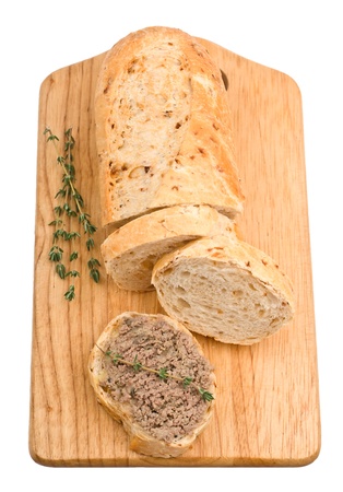 Slice of homemade bread with pate and herbs on a wooden cutting board isolated on white backgroundの写真素材