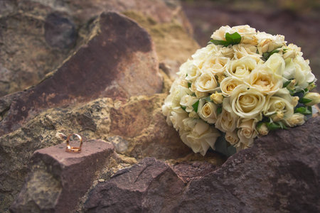 Yellow rose bouquet on stone rock, wedding ringsの写真素材