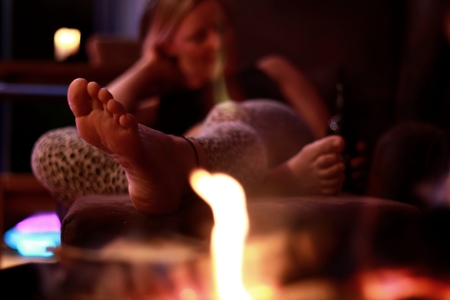 young blond woman is sitting by the fireの写真素材