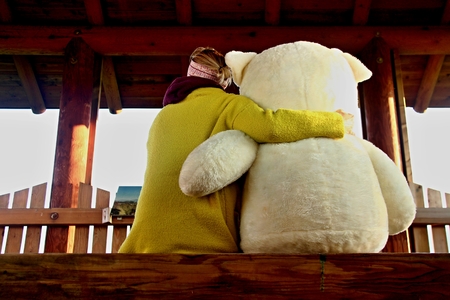 blonde young woman hugs huge teddy bearの写真素材