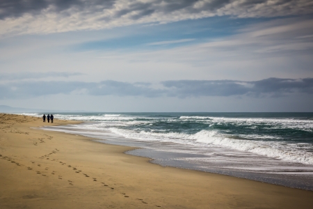 Silhouette of Three Figures on the Beachの写真素材