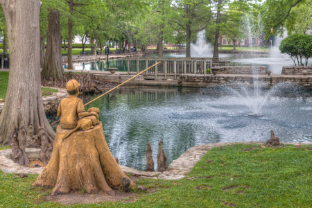STILLWATER, OK/USA - MAY 20, 2016: Boy and Dog Fishing Sculpture at Theta Pond on the campus of Oklahoma State University.のeditorial素材