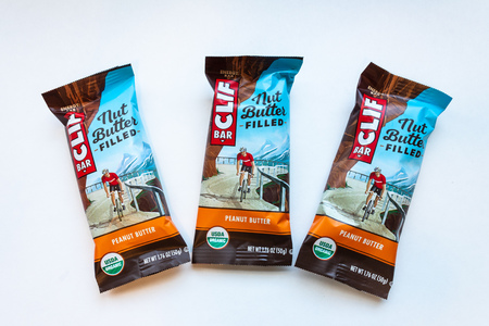 ST. PAUL, MN/USA - FEBRUARY 24, 2019: Clif Bar peanut butter energy bar grouping of three and trademark logo. Clif Bar & Company is an American company that produces organic foods and drinks.のeditorial素材