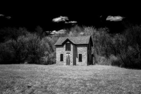 Darkened brick abandoned farm house in secluded forest in black and white.の写真素材