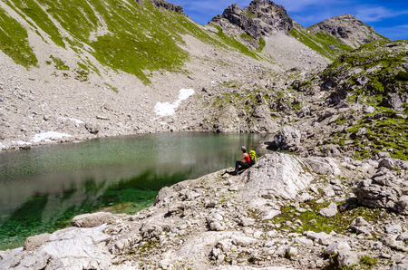 A hiker is recovering beside a mountain lake.の写真素材