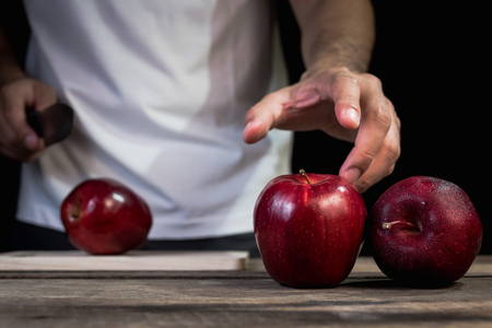 The man cutting red apple on wood tableの写真素材