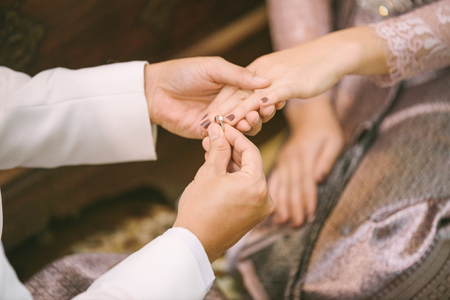 The groom puts the wedding ring to finger of the brideの写真素材